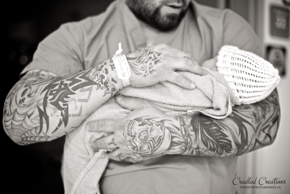 tatood arms holding baby